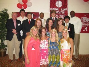 Group standing in room with banners and white wall in background.