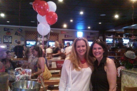 Man in blue shirt and women in red shirt standing in front of dark wall