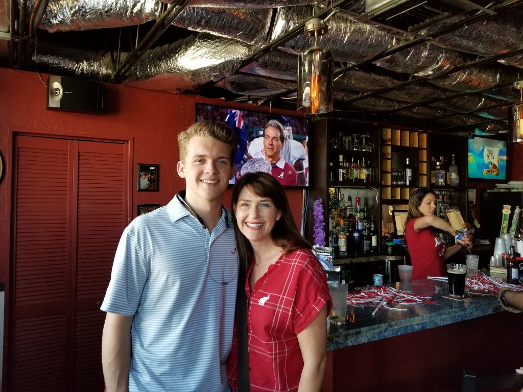 Man in blue shirt and women in red shirt standing in front of dark wall