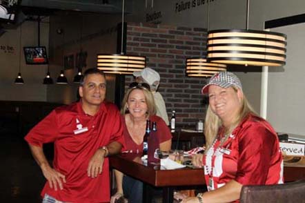 Group of people sitting at table with brick wall in background.