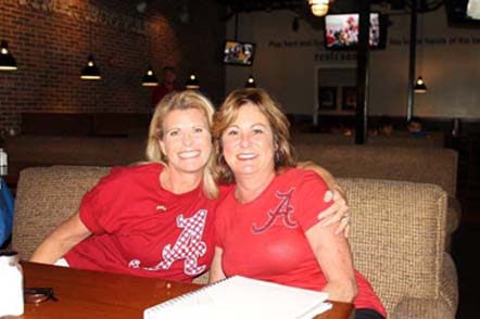 Two ladies in red shirts sitting in room with dim light.