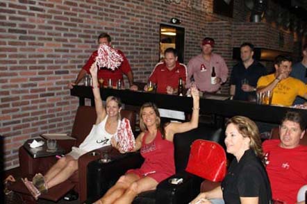 Group of people sitting and standing in room with dim light.