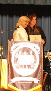 Two ladies standing behind podium in front of gray curtain.