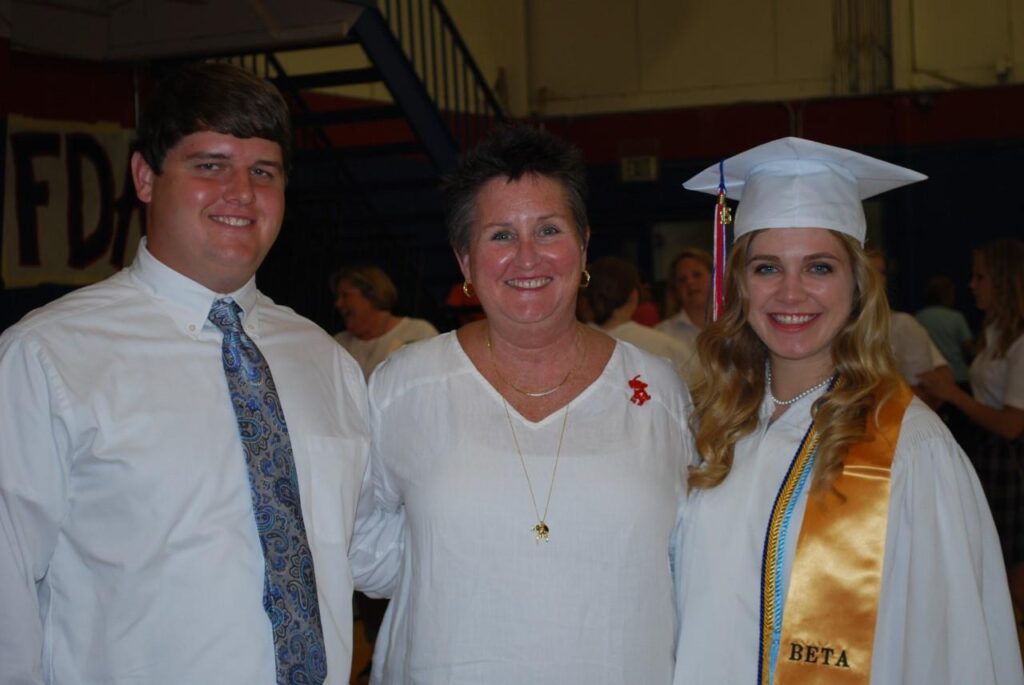 Three people standing in dim light room.