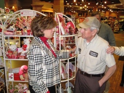 Terry Saban and man in beige shirt and cap standing in front of display.