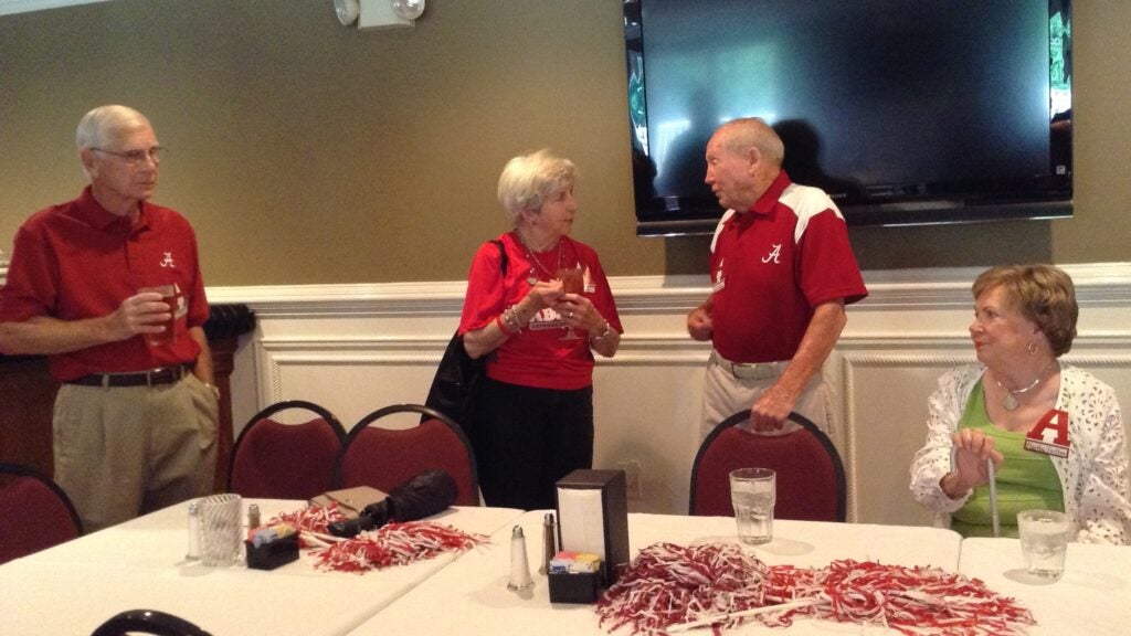 Two people with red shirts standing behind a table.