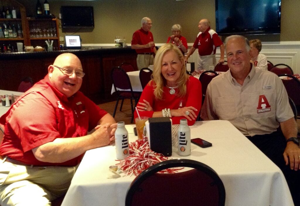 Group of people sitting at a table with people in the background.