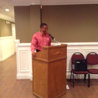 Man in red shirt standing behind a podium.