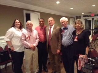 Group of people standing in a room with beige and white walls.