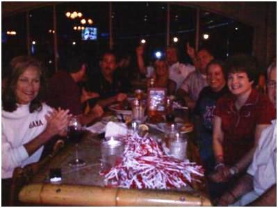 Group of people sitting at table in dim light room.