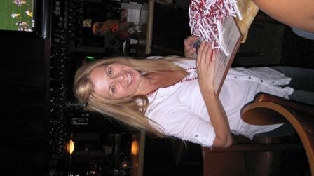 Lady in white shirt standing in dark room.