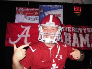 Person in a red shirt and red football helmet standing in front of red banner.