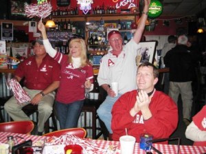 Group of people standing with red and white shakers behind a table.