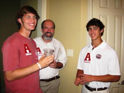 Three people standing in room with beige wall.