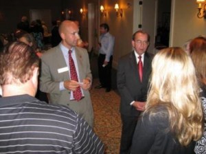 Group of people standing in dim room talking.