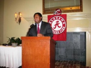 Man in dark suit standing behind podium.