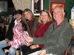 Group of people sitting holding a red and white shaker.