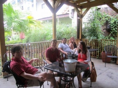 A group of people sitting at a patio table outside.