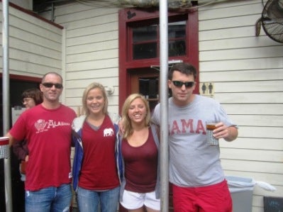 A group of people standing outside in front of a white wall.
