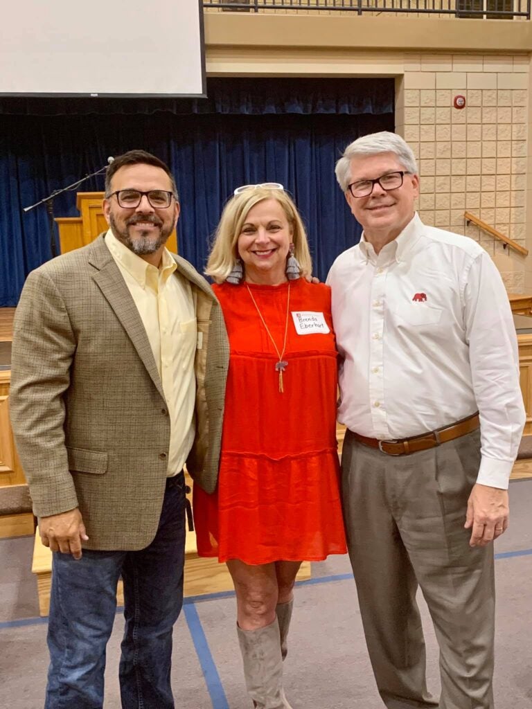 Three people standing in front of dark wall