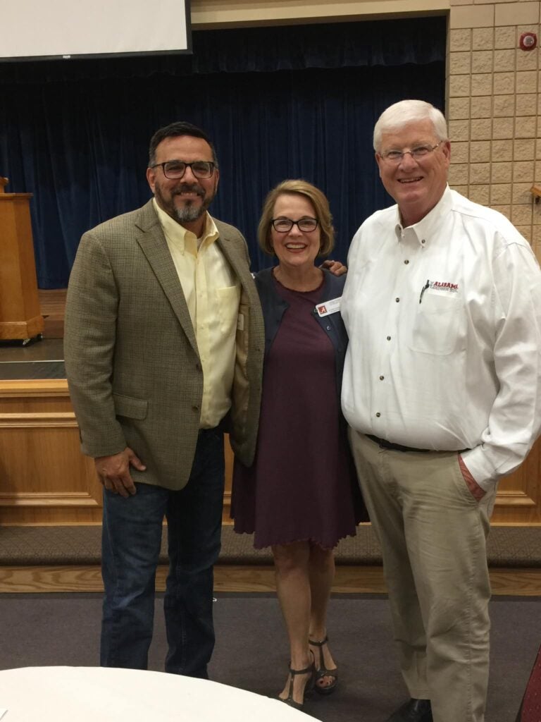 Three people standing in front of dark wall