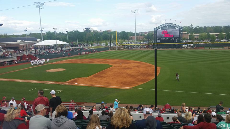 Group of people sitting in stands at baseball field.
