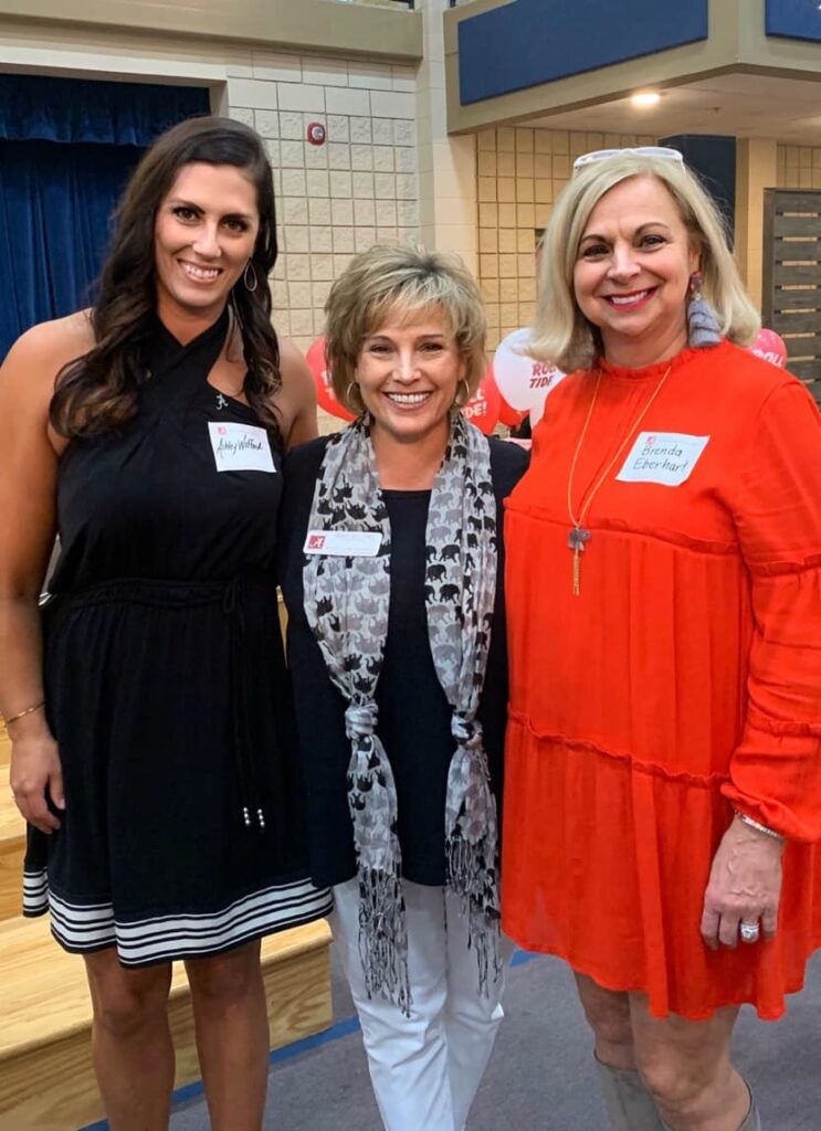 Three ladies standing in front of white wall