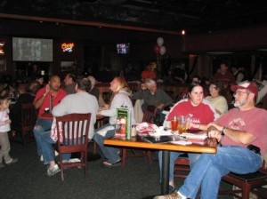 Group of people siting at tables in dim light room.