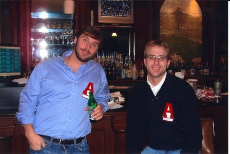 Two people standing in dim light room.