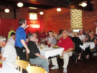 Group of people sitting at table in room with red background.