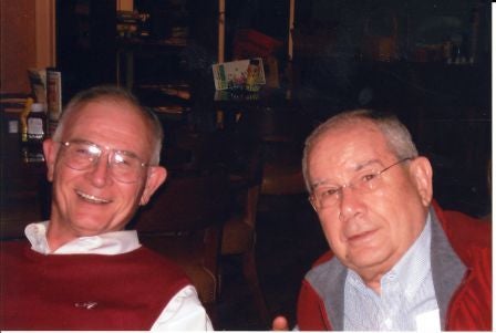 Two people sitting in dim light room.