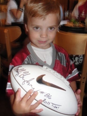 Little boy holding an autographed football.