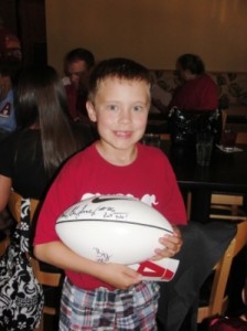 Little boy in red shirt holding football.