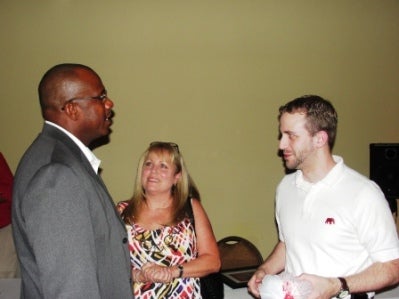 Group of people standing in front of green wall.