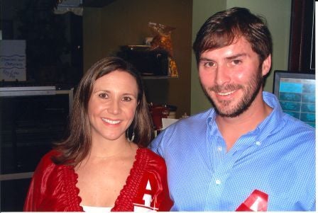 Two people standing in dim light room.