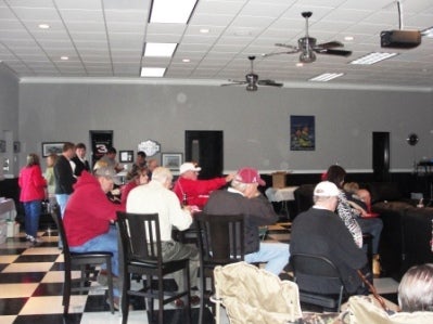 Group of people sitting at table with white wall in background.