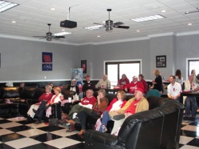 People sitting in room with white walls.
