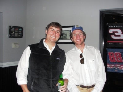 Two people standing in front of white wall.