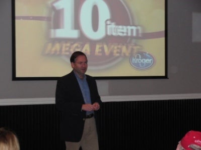 Man in black jacket standing in front of screen.