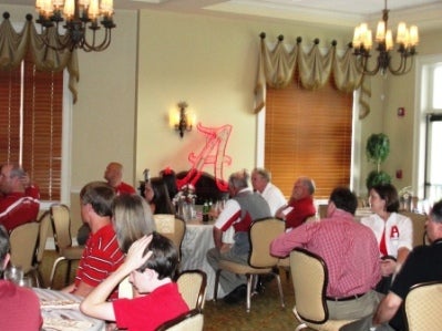 Group of people sitting in room with beige walls.