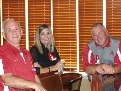 Three people sitting in front of window with brown shades.