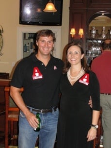Man in black shirt and women in black dress standing in a room with dim light.