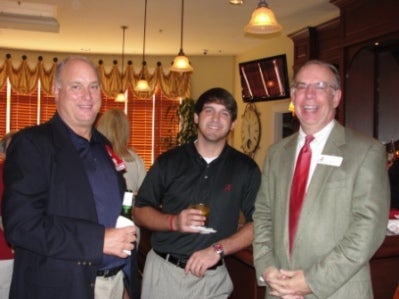 Three men standing in a room with dim light.