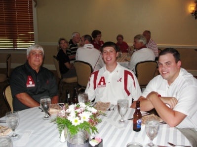 Group of people sitting at tables in a dim light room.