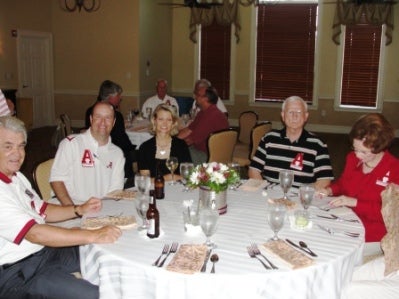 Group of people sitting at tables in a dim light room.