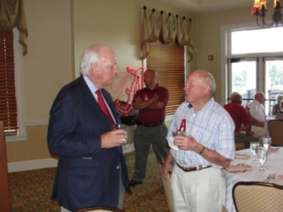 Group of people standing in room with window in background.