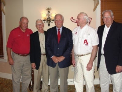 Group of people standing in front of white wall.