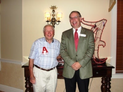 Two peiople standing in front of white wall.