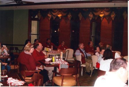 Group of people sittig at a table in dim light room.