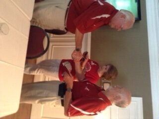 Three people in red shirts standing in a room.